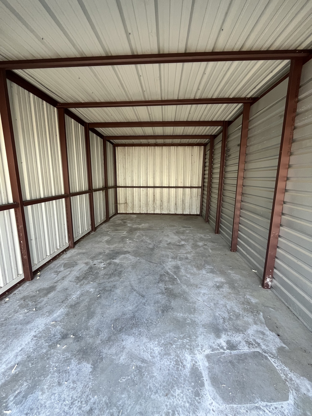 Clean, empty interior of a storage unit at Peculiar Storage showing concrete floor and metal walls